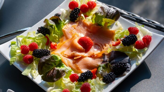 Entzündungshemmende Lebensmittel: Teller mit Räucherlachs, Blattsalat, Himbeeren und Brombeeren