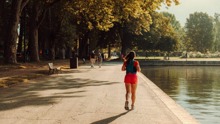 Laufstrecke Mainz: Symbolbild einer Joggerin auf einer baumgesäumten Uferpromenade
