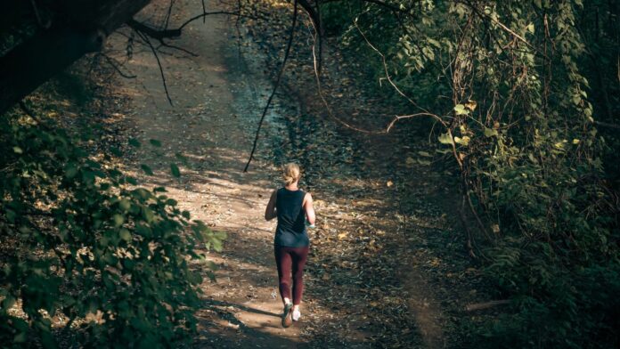 VO2max verbessern: Frau joggt auf einem herbstlichen Waldweg